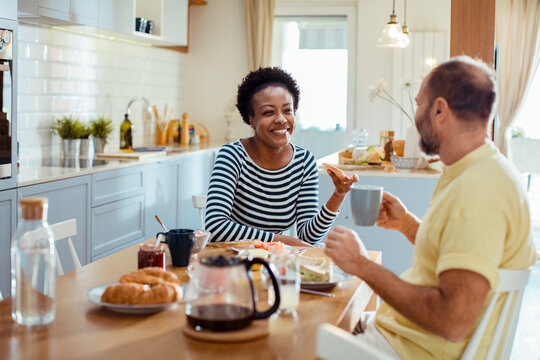 Diverse middle aged couple having breakfast together at home