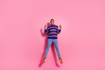 Full length photo of handsome young guy point up empty space jump wear trendy purple striped garment isolated on pink color background