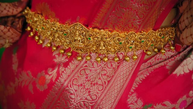 Woman dressed in traditional Indian clothes fixes the decoration, and piaint of hand mehndi. hindu wedding. Close up shot