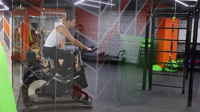 Sportsman trains on bicycle in gym of fitness center 