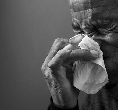 catching the flu and blowing nose after catching a cold with grey black background with people stock image stock photo	