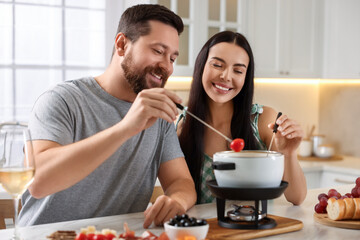 Affectionate couple enjoying fondue during romantic date in kitchen
