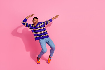 Full length photo of cheerful excited guy dressed striped pullover having fun enjoying disco empty space isolated pink color background