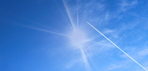 Airplane track. Airplane flying in blue sky among clouds and sunlight. The concept of air transport. - Powered by Adobe