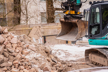 Construction rubble excavator bucket in work during winter construction project