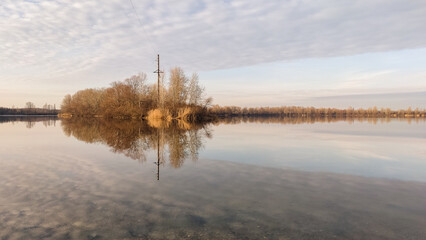 Fototapeta na wymiar Winter landscape without snow, the surface of the river Desenka with reflecting clouds, trees, the beautiful sky and reflection, the distant horizon, nature of Ukraine