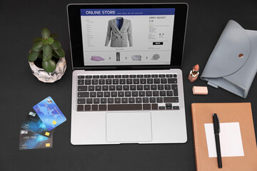 Online store website on laptop screen. Computer, credit cards, women's bag, stationery and lipstick...