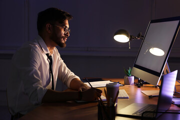 Tired young man working late in office