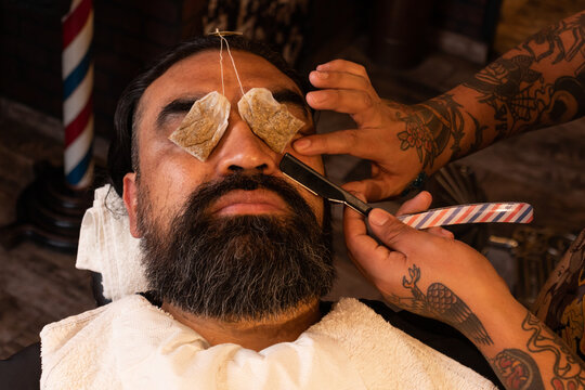 Crop barber trimming mustache of client in barbershop