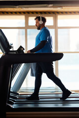 Mature athlete warming up treadmill while exercising in gym.