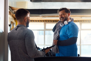 Happy mature man having exercise class with personal trainer in  gym.