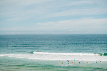 Serene beach scene with distant surfers and swimmers