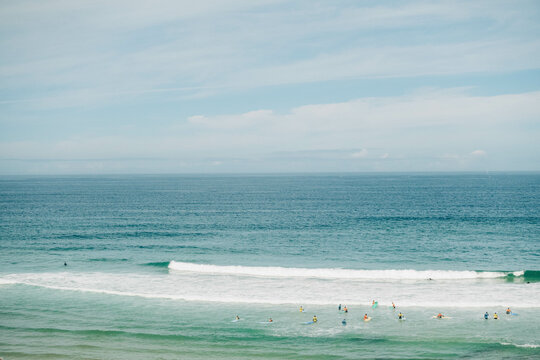 Serene beach scene with distant surfers and swimmers