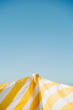 Striped yellow and white sunshade against clear sky