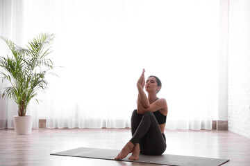Young woman practicing eagle asana in yoga studio. Garudasana pose