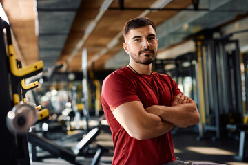 Fototapeta na wymiar Confident personal trainer with arms crossed in gym looking at camera.