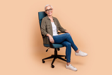 Full length photo of lovely pensioner lady sitting armchair office manager wear trendy khaki garment isolated on beige color background