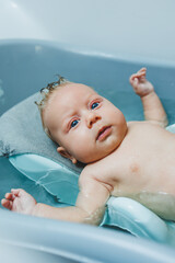 A newborn baby takes a bath. Parents bathe the child. The newborn is bathed. The newborn is smiling. Baby care