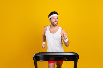 Photo of purposeful funky guy activewear running treadmill looking empty space isolated yellow...