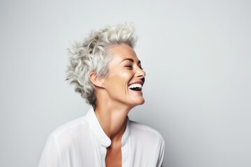 Portrait of a happy senior woman laughing and looking up over grey background