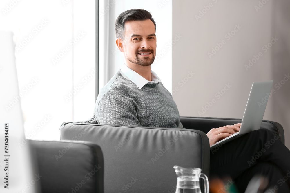 Wall mural Handsome businessman working with laptop in office