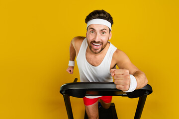 Photo of impressed funky guy sportswear running fast treadmill empty space isolated yellow color...