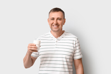 Mature man with glass of milk on white background