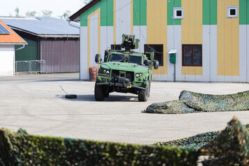 A green armored and camouflaged military vehicle driving at a show