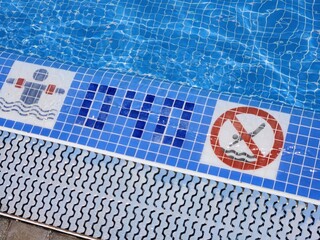 A view of the pool edge with specified depth for safe swimming and a warning sign prohibiting diving. Spain. - obrazy, fototapety, plakaty