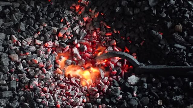 A piece of bronze is being burned on burning coal in a factory. A traditional copper and brass household appliance factory.