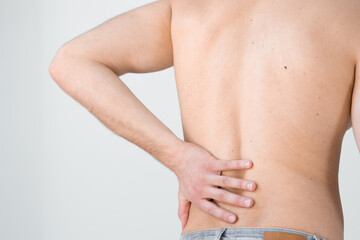 Fototapeta na wymiar Rear view of a shirtless handsome young man holding his back in pain isolated on white background, muscular attractive man touching his lower back, back pain