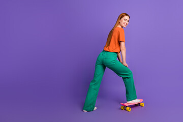 Fototapeta na wymiar Full length photo of redhair student girl riding mini skateboard near empty space sports equipment shop isolated on purple color background