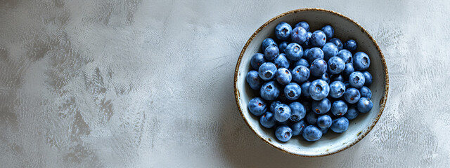 Blueberries in ceramic bowl on textured grey background. Wide panoramic shot. Clean eating and...