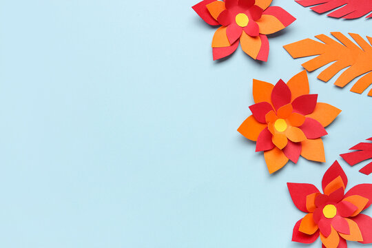 Colorful origami flowers with leaves on blue background