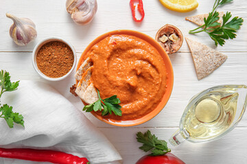 Bowl of tasty muhammara and ingredients on white wooden background