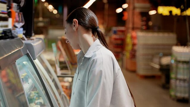 Beautiful woman chooses fresh salmon fish in a supermarket