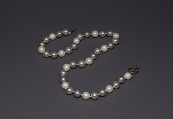 Pearl white round beads on a gray background. Women's elegant jewelry.