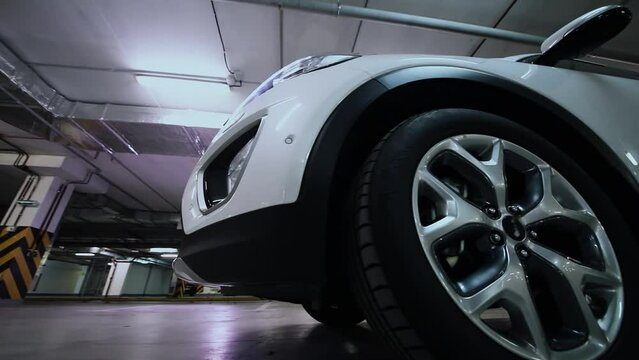Wheel of white car which stand on underground parking