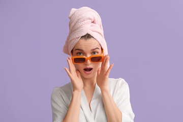 Shocked young woman in sunglasses after shower on lilac background. closeup