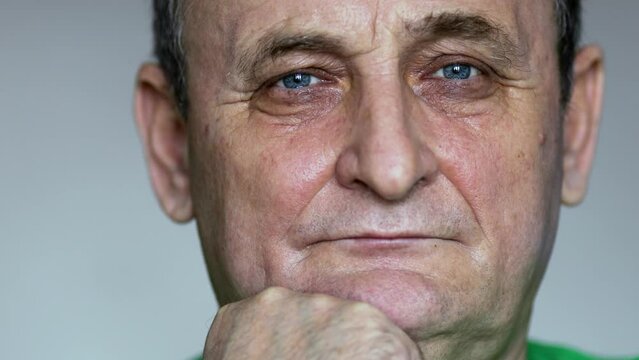 Face of aged man which leans chin on fist at light background