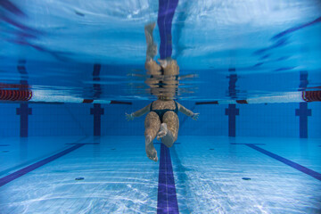 Underwater photo, girl swimming in a sports pool, rear view.