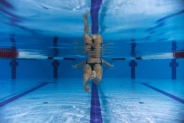 Rolgordijnen Underwater photo, girl swimming in a sports pool, rear view. © Dmitri
