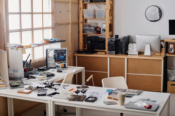 Empty workshop interior with big amount of tools and elements of faulty electronic devices displayed on table