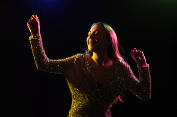 Silhouette of young woman dancing on dark background