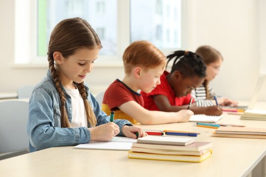 Cute children studying in classroom at school - Powered by Adobe