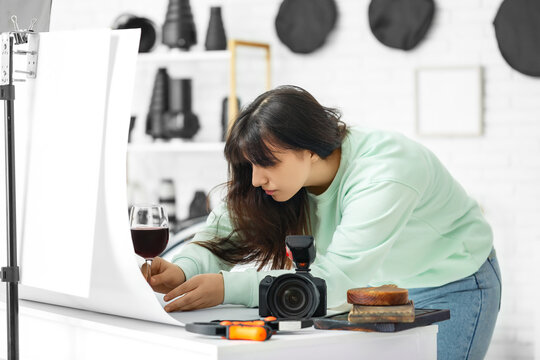 Female food photographer preparing for shooting wine in studio
