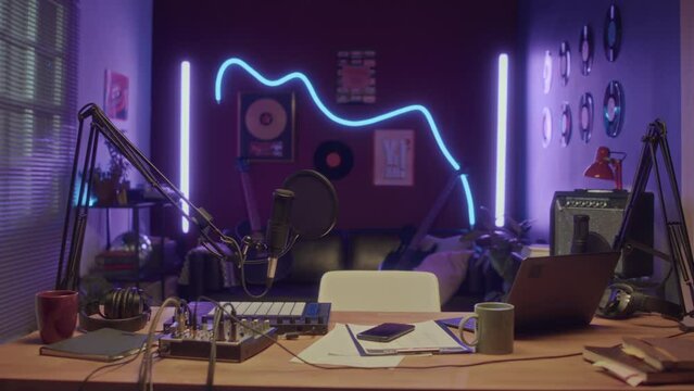 No people footage of interior of empty neon lit home recording studio with professional microphone, sampler, mixing console and laptop for creating music