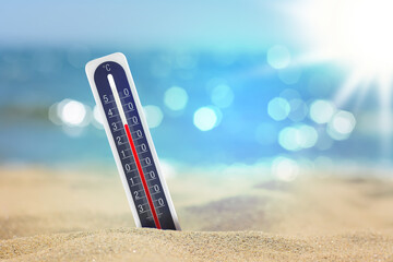 Thermometer on beach showing high temperature during summer day