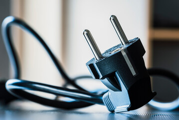 Electric plug close-up with power supply cord cable on metal surface