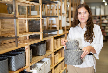 Young attractive european woman customer standing with wicker basket in shop for decor
